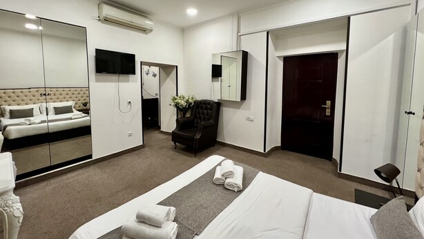 Een hotelkamer met een bed, een zithoek met een stoel, een televisie, een spiegel en een kledingkast.