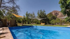 Una piscina rectangular amb vora blava, envoltada d'un tram buidor de fusta.