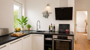 A modern kitchen with a Bosch dishwasher, a toaster, a sink, and a flat-screen TV mounted above the counter.