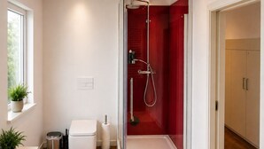 A modern bathroom with a glass-enclosed shower, a toilet, and a sink.
