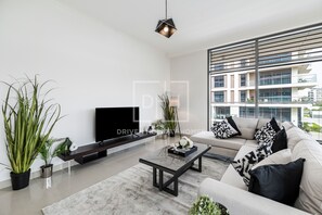 A modern living room with a sofa, coffee table, TV, and plants. - Corner Unit Mulberry Dubai Hills Estate (Dubai)