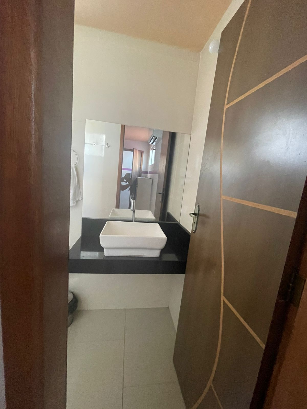 Un bagno con un lavandino bianco, uno specchio e una porta.
