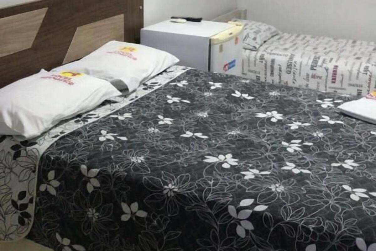 Habitación de hotel con una cama, una mesita de noche y un estante en la pared.
