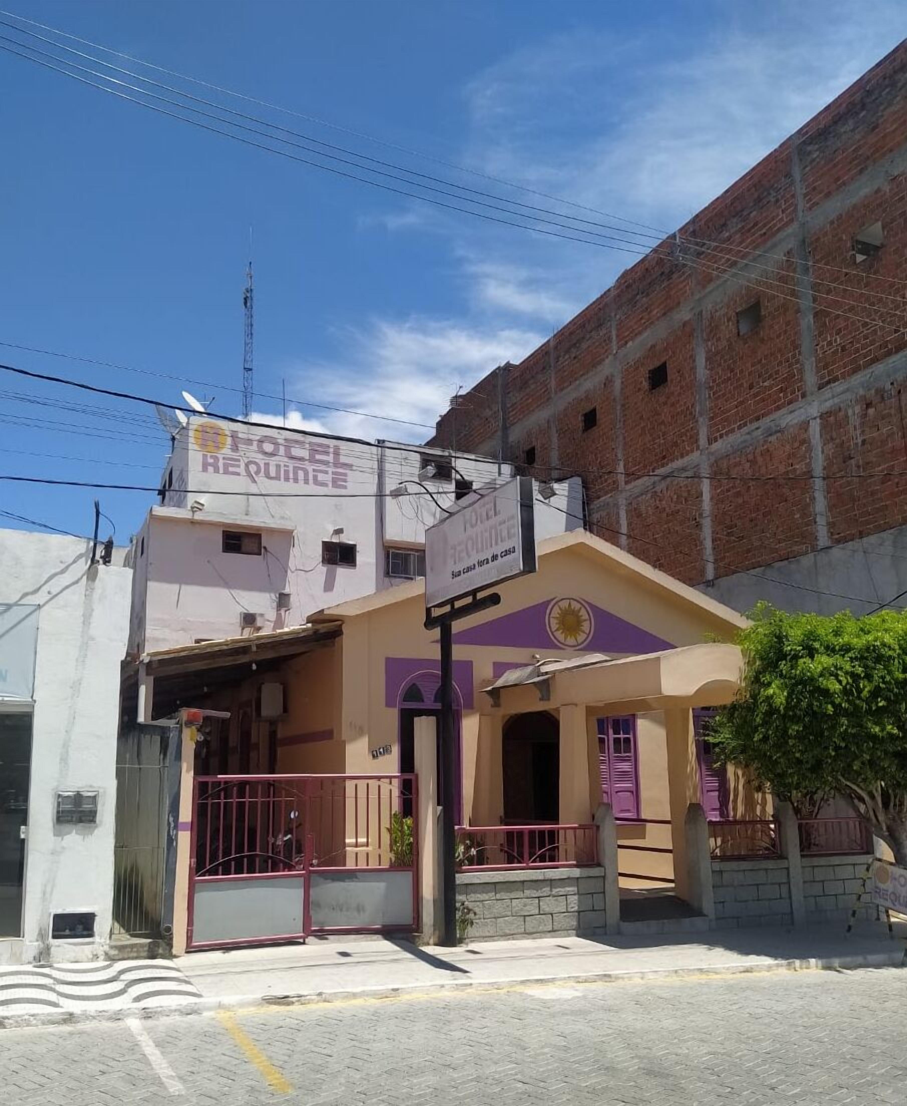 A hotel with a purple and yellow facade, a gated entrance, and a sign indicating it is a hotel.