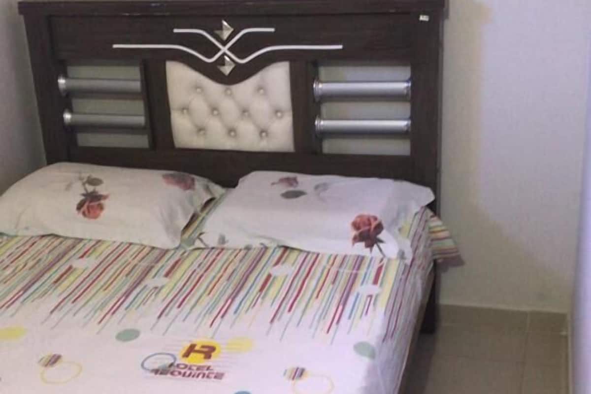 Un dormitorio con una cama, un cabecero con un logotipo circular y un interruptor de luz en la pared.