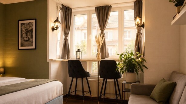A room with a bed, two chairs, a table, a potted plant, a lamp, and a framed picture on the wall. - Stylish & Quiet Studio | Parking | WIFI | TV (Bielefeld)