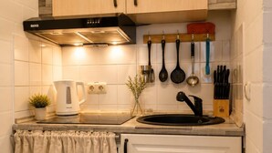 A compact kitchen with white cabinets, a black range hood, a kettle, and a sink. - Stylish & Quiet Studio | Parking | WIFI | TV (Bielefeld)