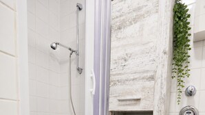 A bathroom with a shower, toilet, and a shelf with toiletries. - Stylish & Quiet Studio | Parking | WIFI | TV (Bielefeld)