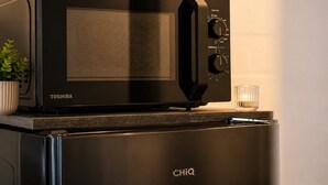 A black Toshiba microwave oven on top of a black refrigerator with the brand name 'CHIQ' on it. - Stylish & Quiet Studio | Parking | WIFI | TV (Bielefeld)