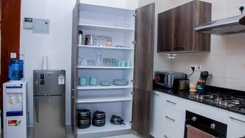 Business appartement | Privékeuken | Een koelkast, een microgolfoven, kookgerei, borden en bestek