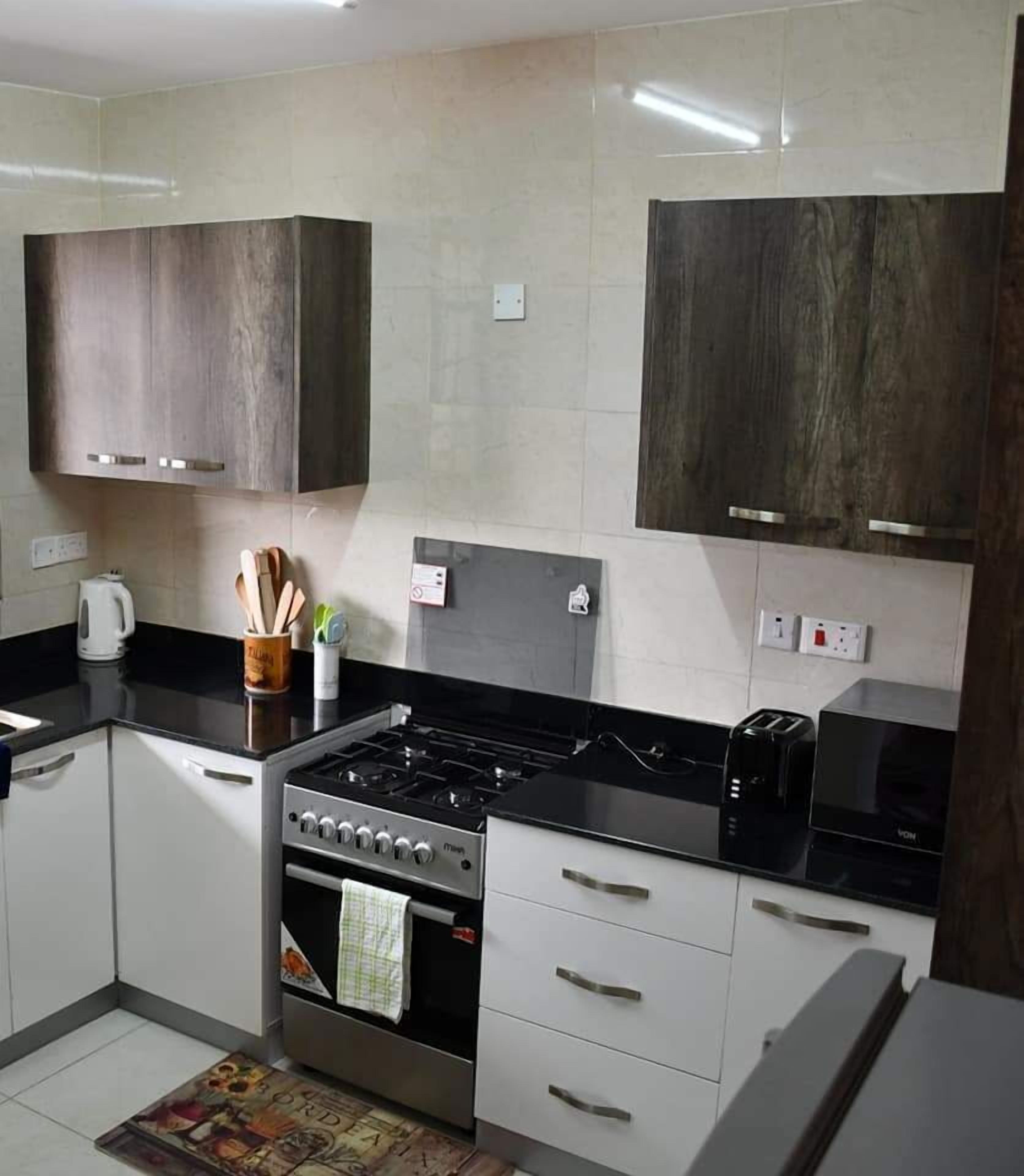 Een moderne keuken met witte kastjes, een zwart aanrecht, een kookplaat en een broodrooster.