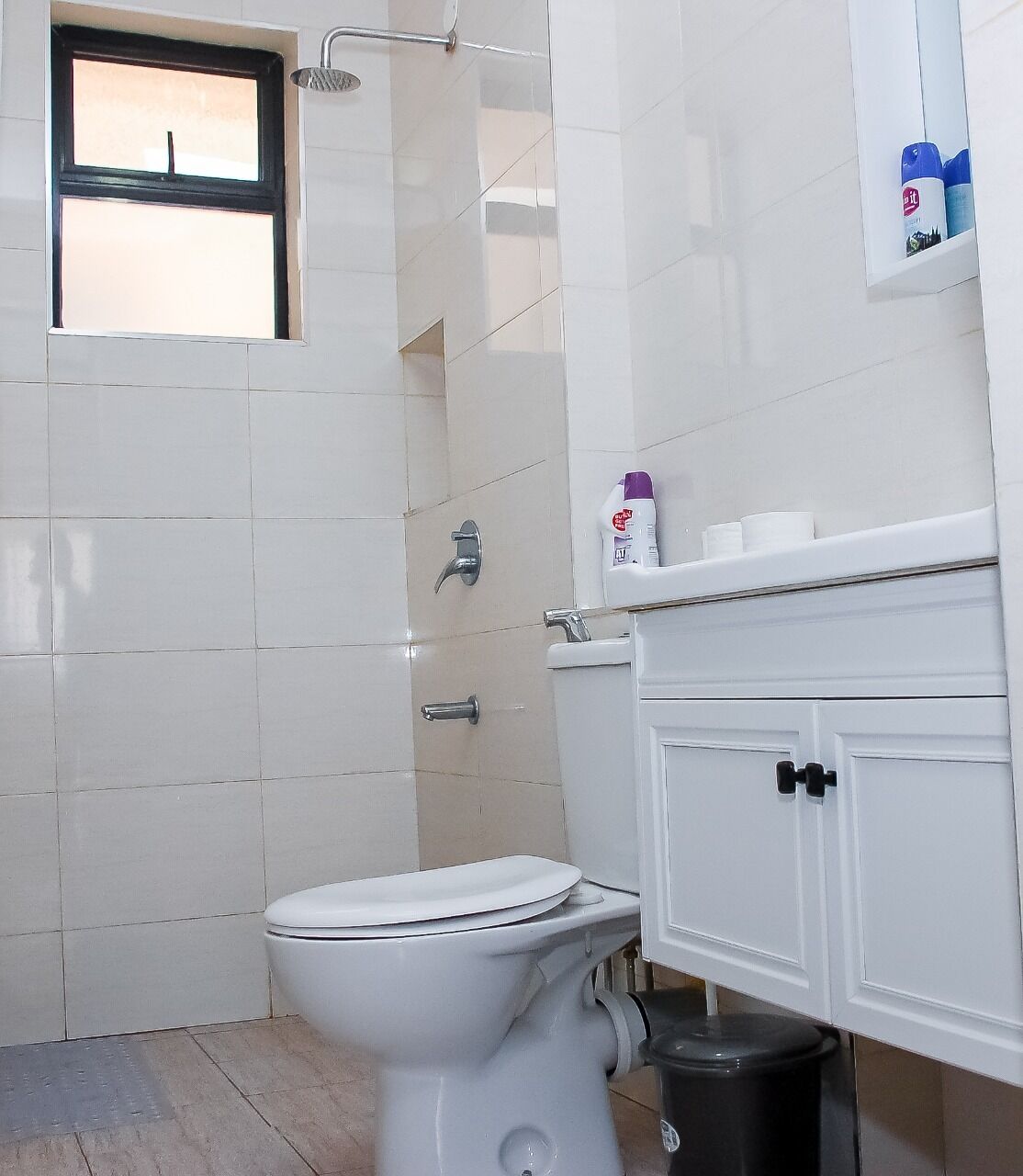 A bathroom with a toilet, a shower, and a window.
