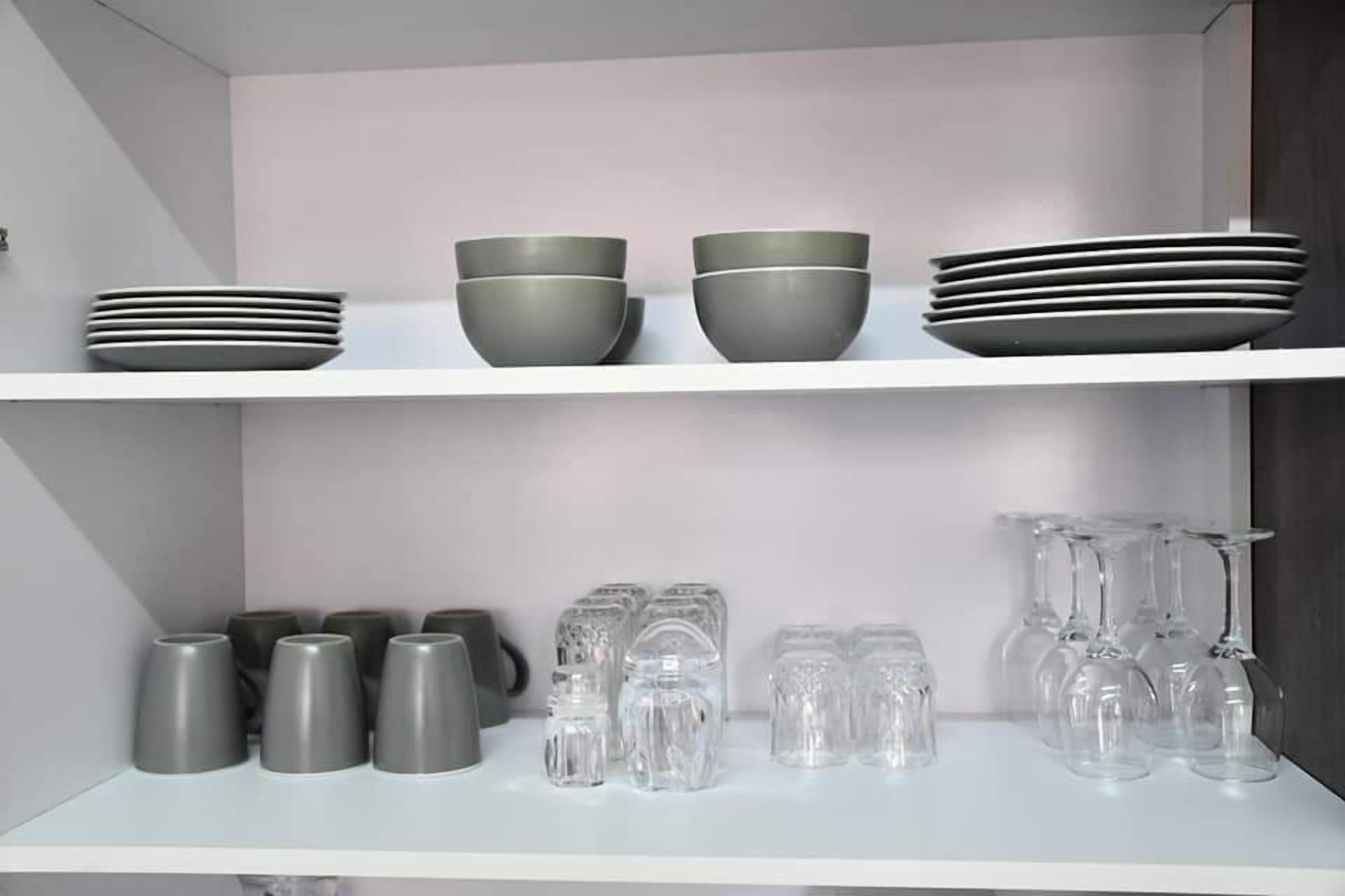A kitchen with two white shelves, each holding various kitchenware items.