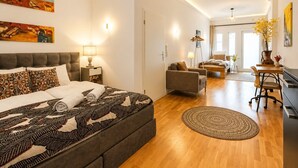 Ein modernes Hotelzimmer mit einem großen Bett, einem Schreibtisch, einer Sitzecke und einem Essbereich.