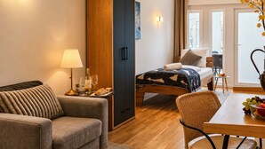 Ein modernes Hotelzimmer mit einem Bett, einer Couch, einem Esstisch und einem Kleiderschrank.