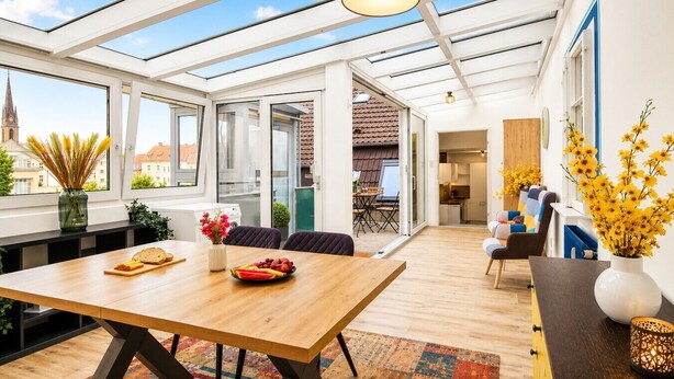 Ein modernes Interieur mit einem Holztisch, einer Küchenzeile und einem Wohnbereich mit Blick auf die Stadt.