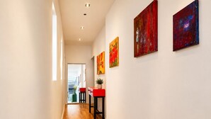 Ein Flur mit Holzboden, einer roten Bank und zwei roten Bildern an der Wand.