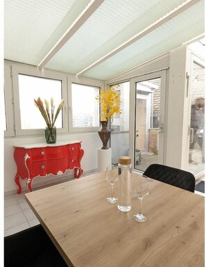 A dining area with a table for two, a sideboard, and a chair, perfect for intimate meals.