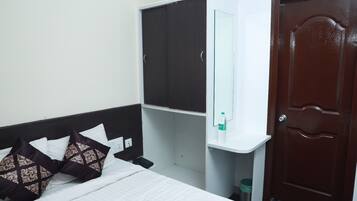 Un dormitorio con cama, armario, espejo, botella de agua y una puerta.