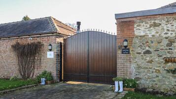 A brick building with a large wooden gate, a stone wall, and a sign that reads "Garden Cottage."