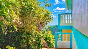 A pathway leading to a building with a blue exterior and a balcony with a white railing. - Blue Whale Villa - Penthouse (Calibishie)