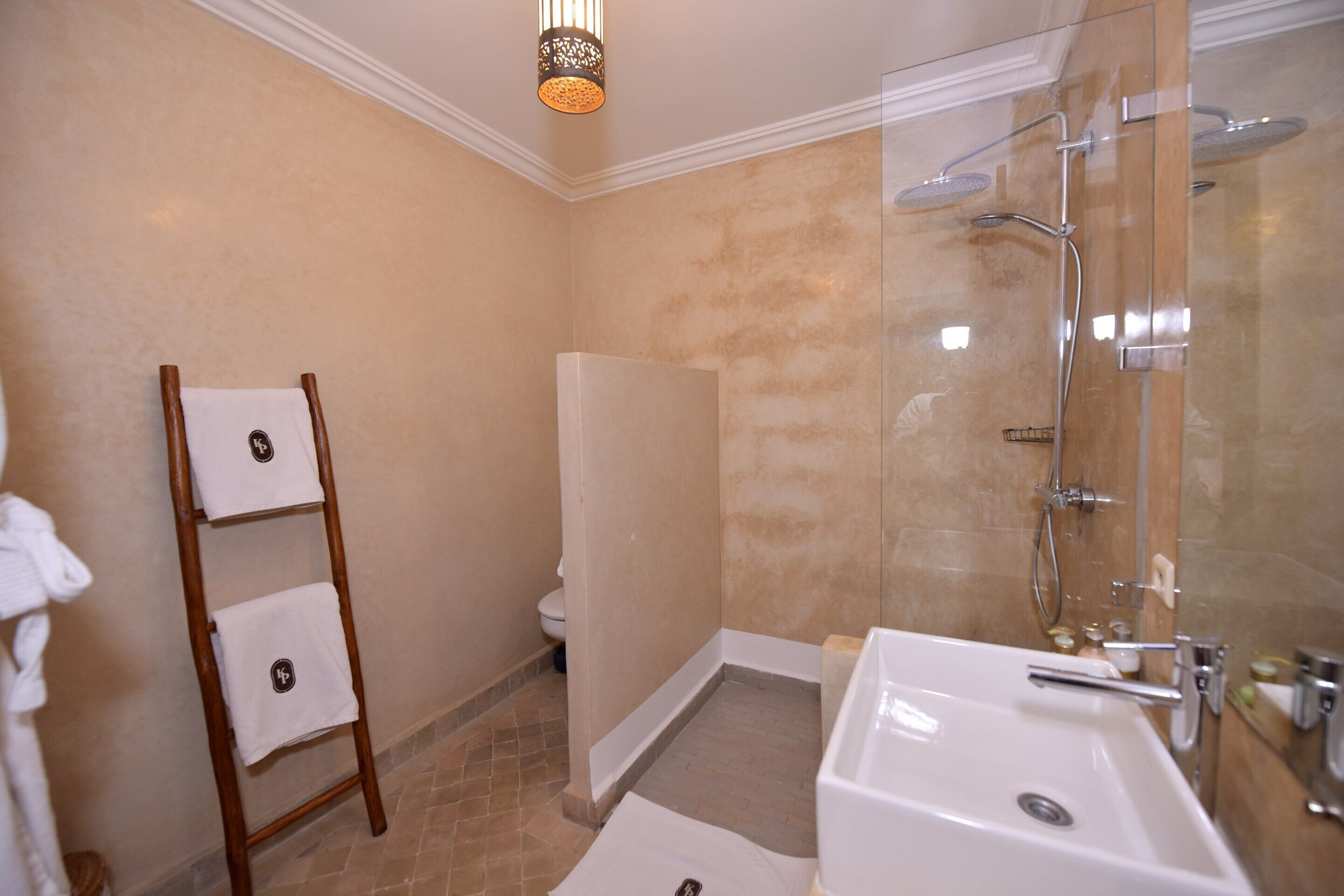 A bathroom with a shower, a sink, a toilet, and a towel rack.