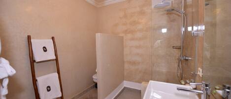 A bathroom with a shower, a sink, a toilet, and a towel rack.