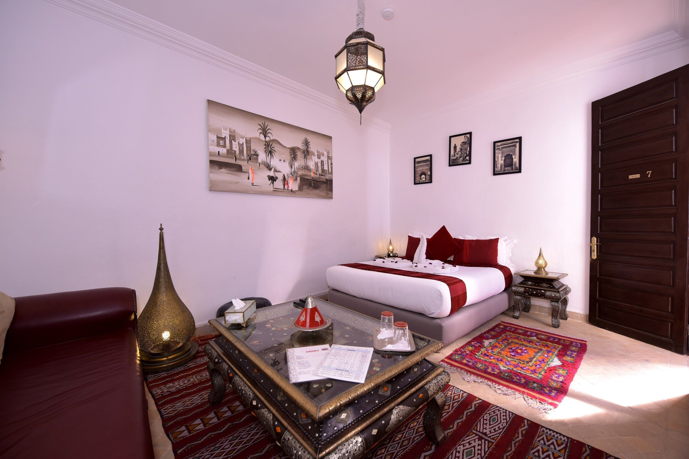 Une pièce comprenant un lit, un canapé, une table basse, une lampe et un tableau accroché au mur.