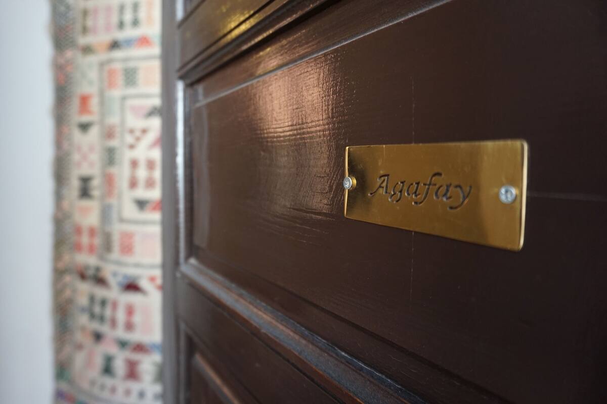 A dark wooden door with a brass nameplate reading 'Agafay.'