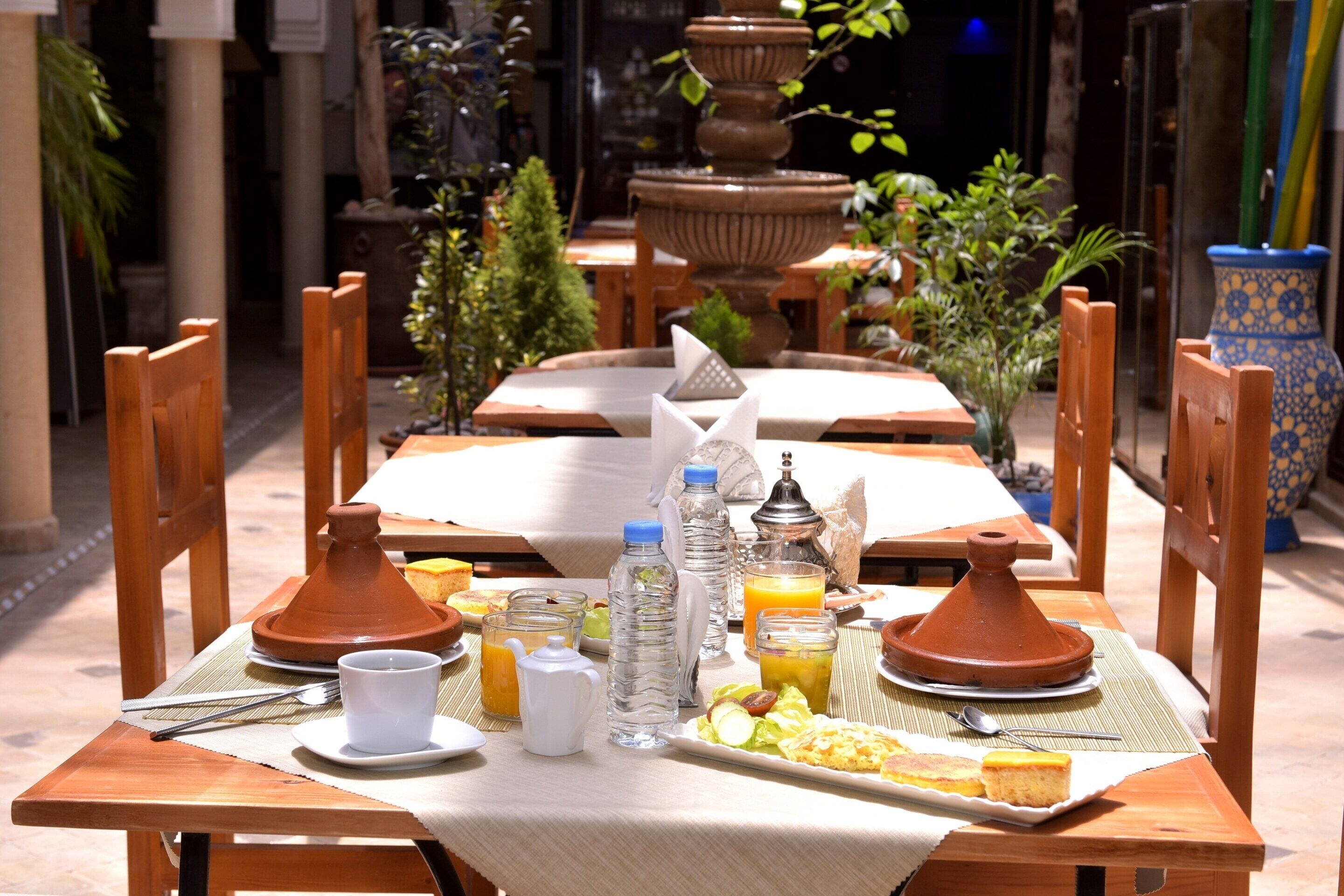 A dining table set with a plate of food, a water bottle, a jug, and a teapot.