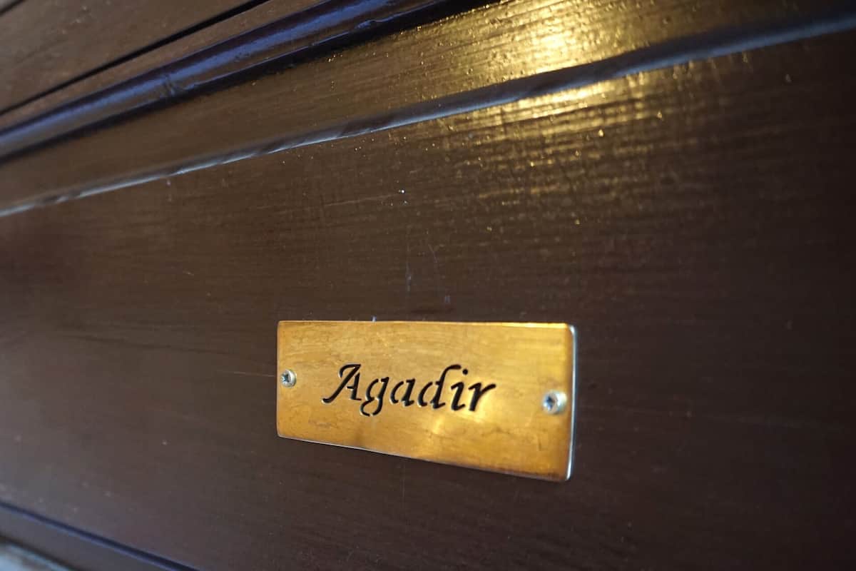 A brass nameplate with the inscription 'Agadir' on a dark wooden surface.