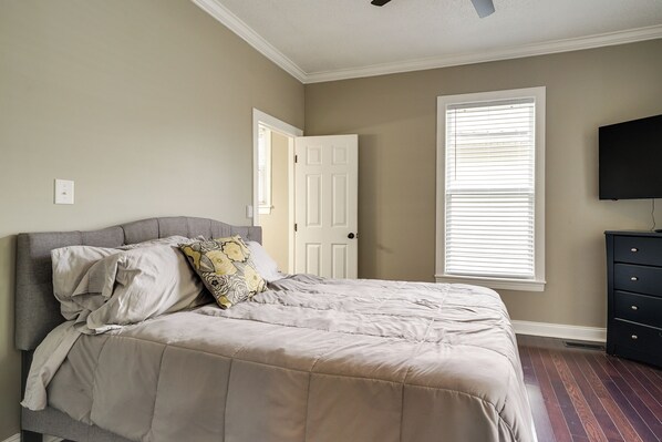 A bedroom with a bed, a dresser, a television, and a door. - Downtown Wilmington Home: Walk to Cape Fear River! (Wilmington)