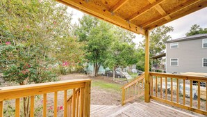 A wooden deck with a railing, surrounded by trees and a house in the background. - Downtown Wilmington Home: Walk to Cape Fear River! (Wilmington)