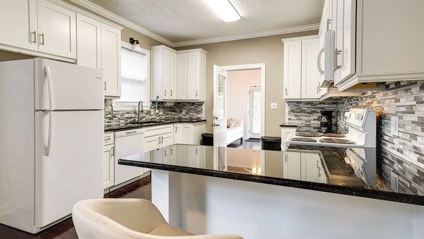 A modern kitchen with white cabinets, a black countertop island, and a built-in stove. - Downtown Wilmington Home: Walk to Cape Fear River! (Wilmington)