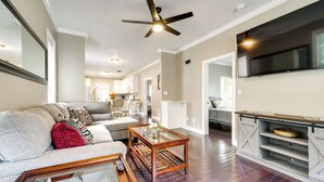A living room with a sofa, coffee table, and TV stand. - Downtown Wilmington Home: Walk to Cape Fear River! (Wilmington)