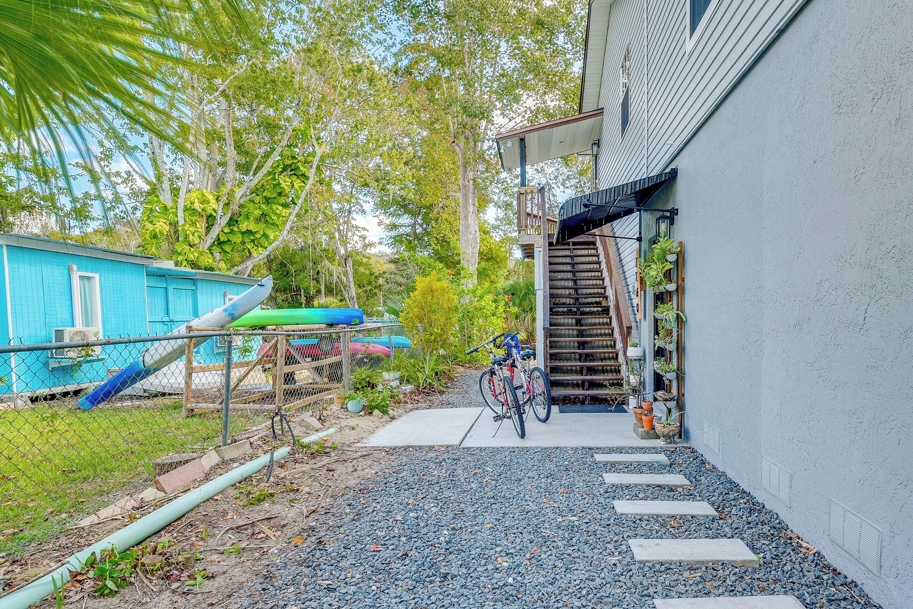 Un jardin avec une maison bleue, un vélo et un escalier menant à une terrasse.