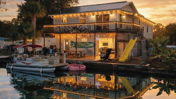 A two-story house with a balcony, a slide, and a dock with boats.