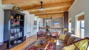 A spacious living room with a wooden ceiling, a bookshelf, a sofa, and a dining area.