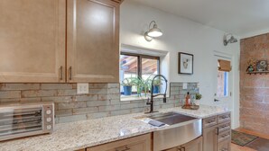 A kitchen with wooden cabinets, a stainless steel sink, granite countertops, and a built-in toaster.