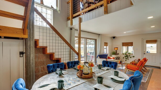 A spacious dining area with a high ceiling, a staircase, and a view of the outdoors.
