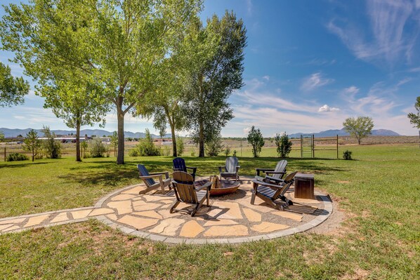 Un área de patio al aire libre con un brasero y sillas Adirondack.