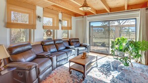 A spacious living room with a leather sectional sofa, a wooden coffee table, and a large window offering a view of the outdoors.
