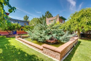 Un patio con fuente de agua, un árbol pequeño y un muro de ladrillo.