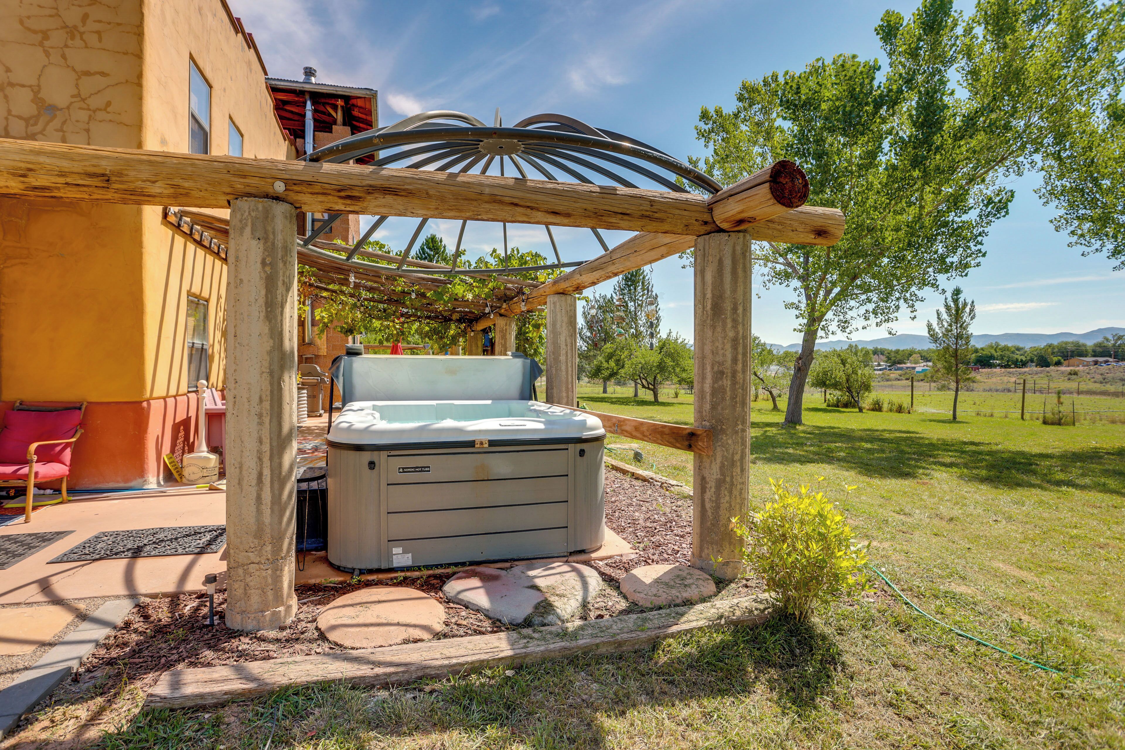 Un jacuzzi bajo una pérgola de madera en un jardín.