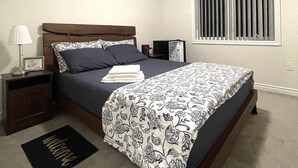 Une chambre à coucher avec un lit, une table de chevet, une lampe et une fenêtre avec des stores.