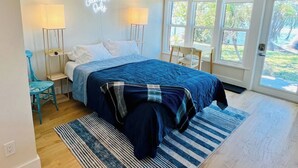 Ein Schlafzimmer mit einem großen Bett, zwei Nachttischlampen, einem Neonzeichen, einem kleinen Tisch und einem Sessel.