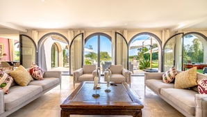 A spacious living room with a large coffee table, two sofas, and a view through arched windows. - Magnificient Villa totally renovated in 2023 with sea view and Saint Tropez   (Grimaud)
