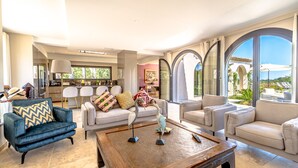 A spacious living room with a modern design, featuring a blue armchair, beige sofas, and a wooden coffee table. - Magnificient Villa totally renovated in 2023 with sea view and Saint Tropez   (Grimaud)