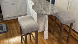 A kitchen with white cabinets, a granite countertop, and two bar stools with cushioned seats. - The Blue backyard studio suite!!  Convenience and practicality in one place!! (Allentown)