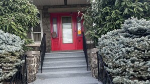 A set of concrete steps leading to a red door with a window, flanked by stone walls and greenery. - The Blue backyard studio suite!!  Convenience and practicality in one place!! (Allentown)
